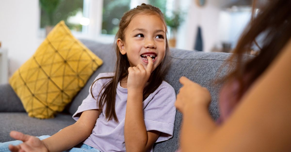 Young girl proudly pointing to her missing front tooth