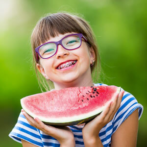 Young girl with braces eating a slice of watermelon
