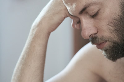 Tired person sitting on the edge of the bed