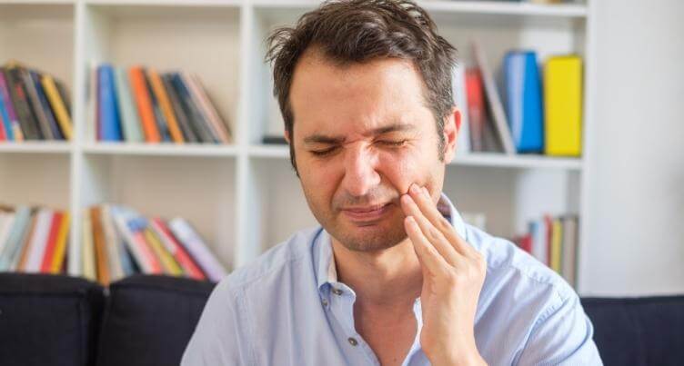 Man holding his cheek, experiencing gum discomfort