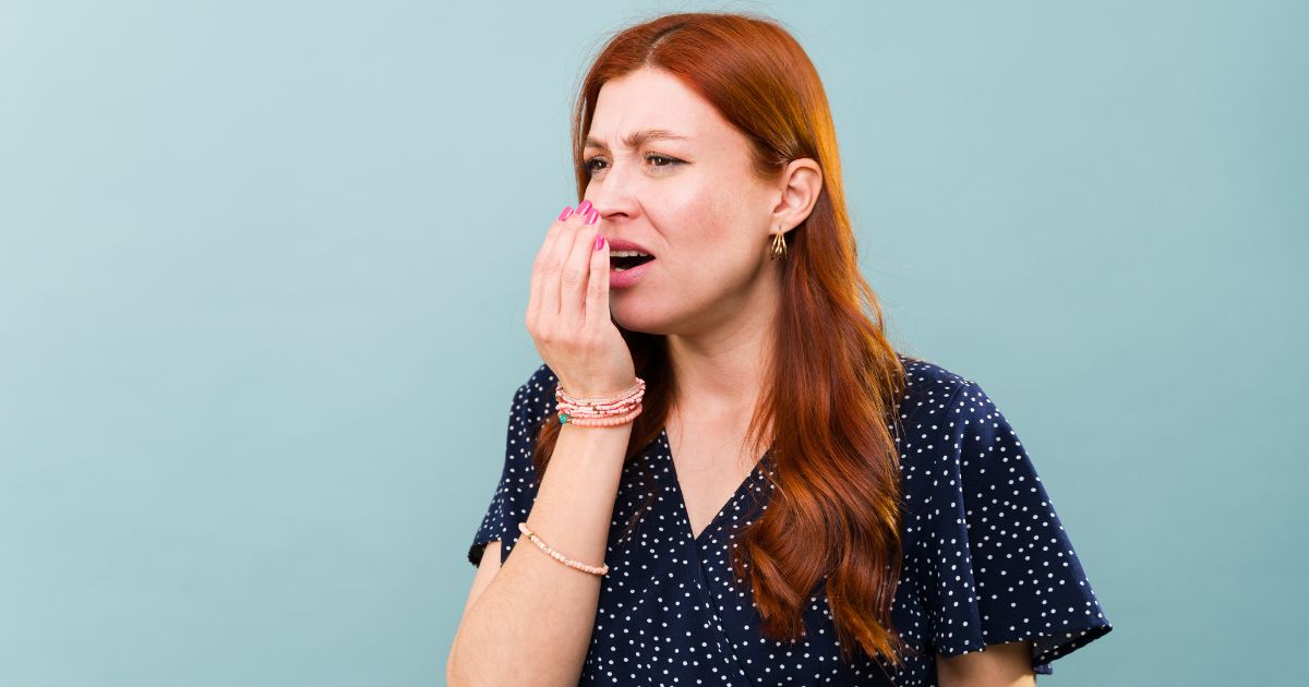 Person checking their breath with a hand