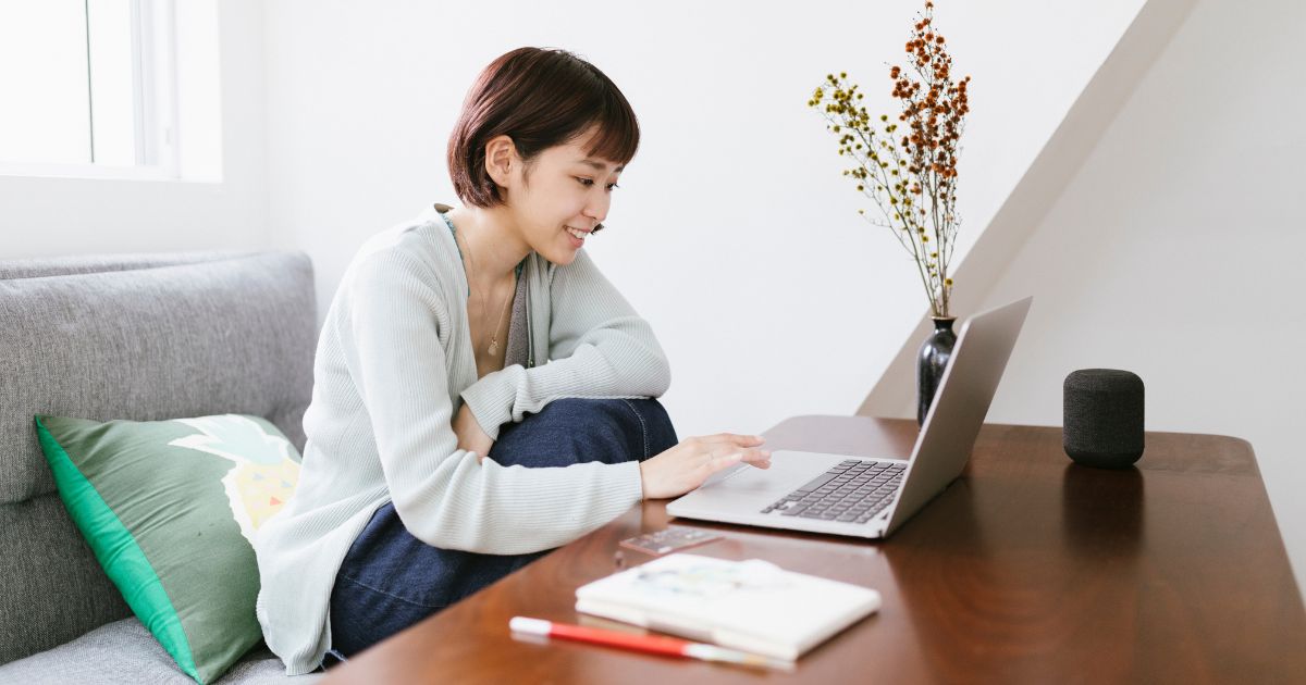 Woman working from home on a couch with a laptop