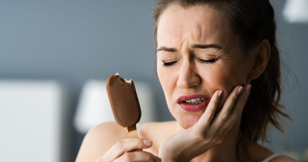 Woman wincing while eating ice cream