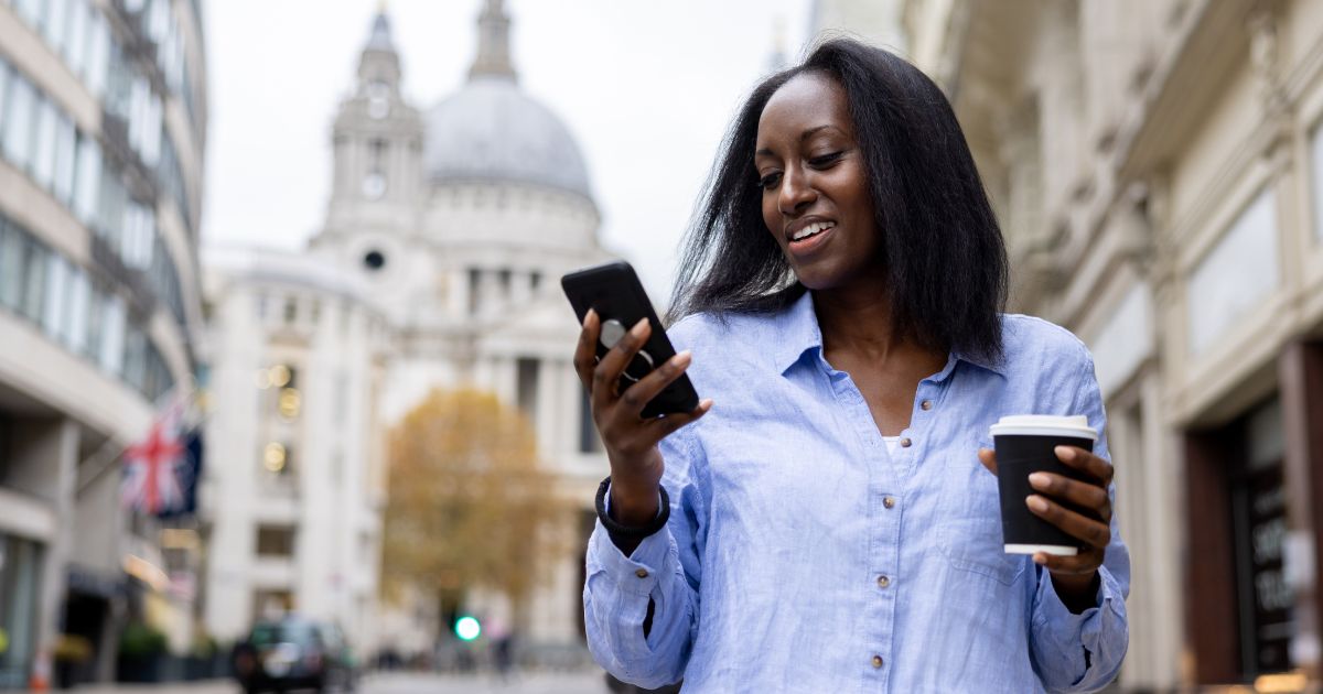 Busy woman walking while holding her phone and a coffee