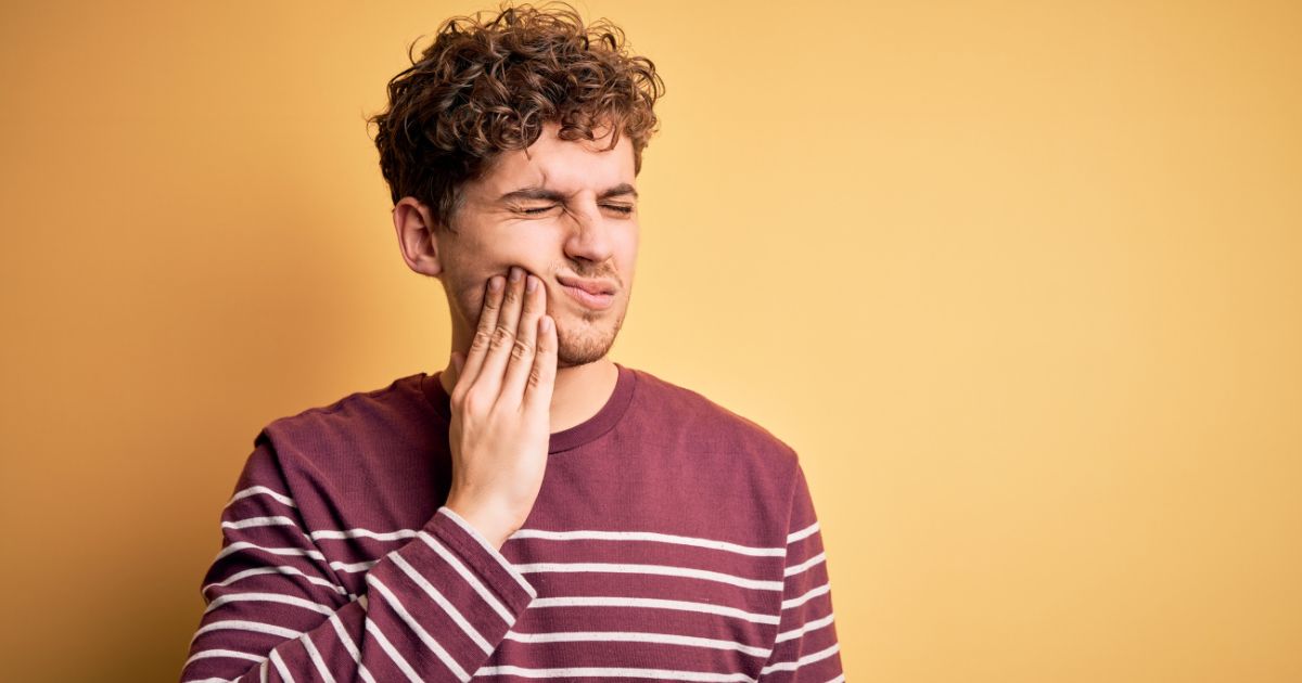 Man holding his cheek, wincing in discomfort