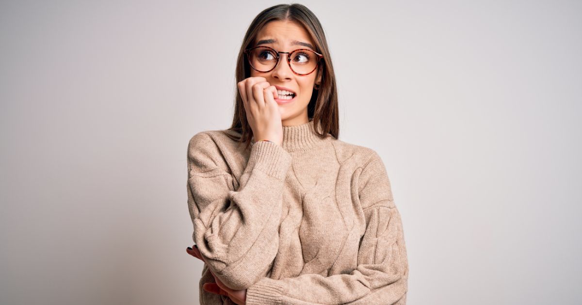 Woman biting her nails, looking stressed