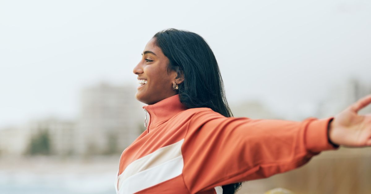 Woman smiling with her arms outstretched outdoors