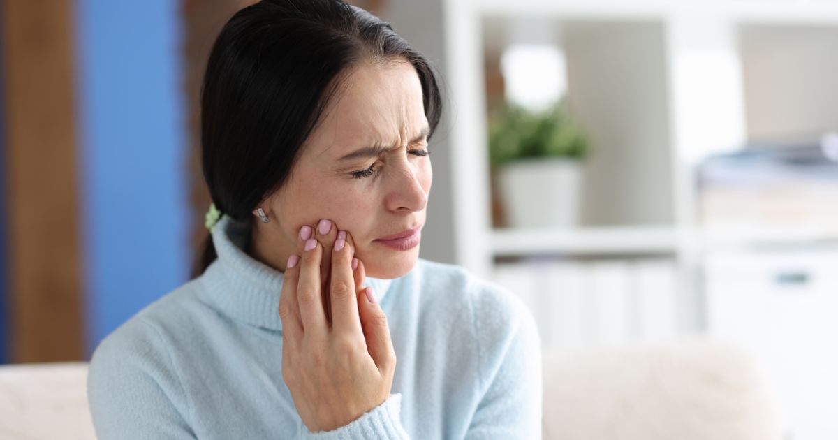 Woman holding her jaw, looking uncomfortable