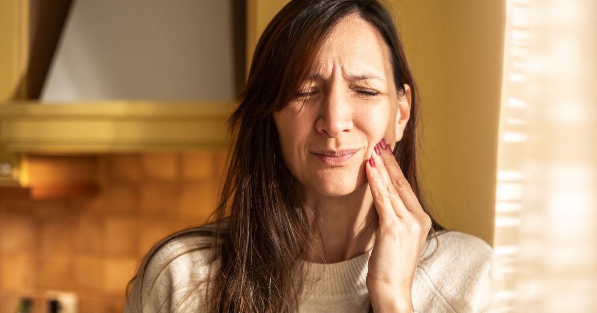 Woman holding her jaw, experiencing pain