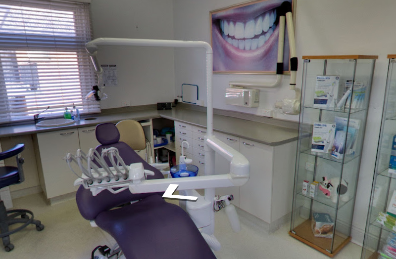 Second treatment room with dental chair, overhead light and display cabinet