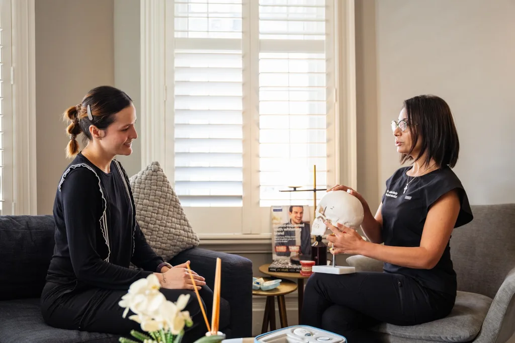 Dr Julie Ghaly explaining jaw anatomy with a skull model to a patient at TMJ Therapy Centre in Toorak