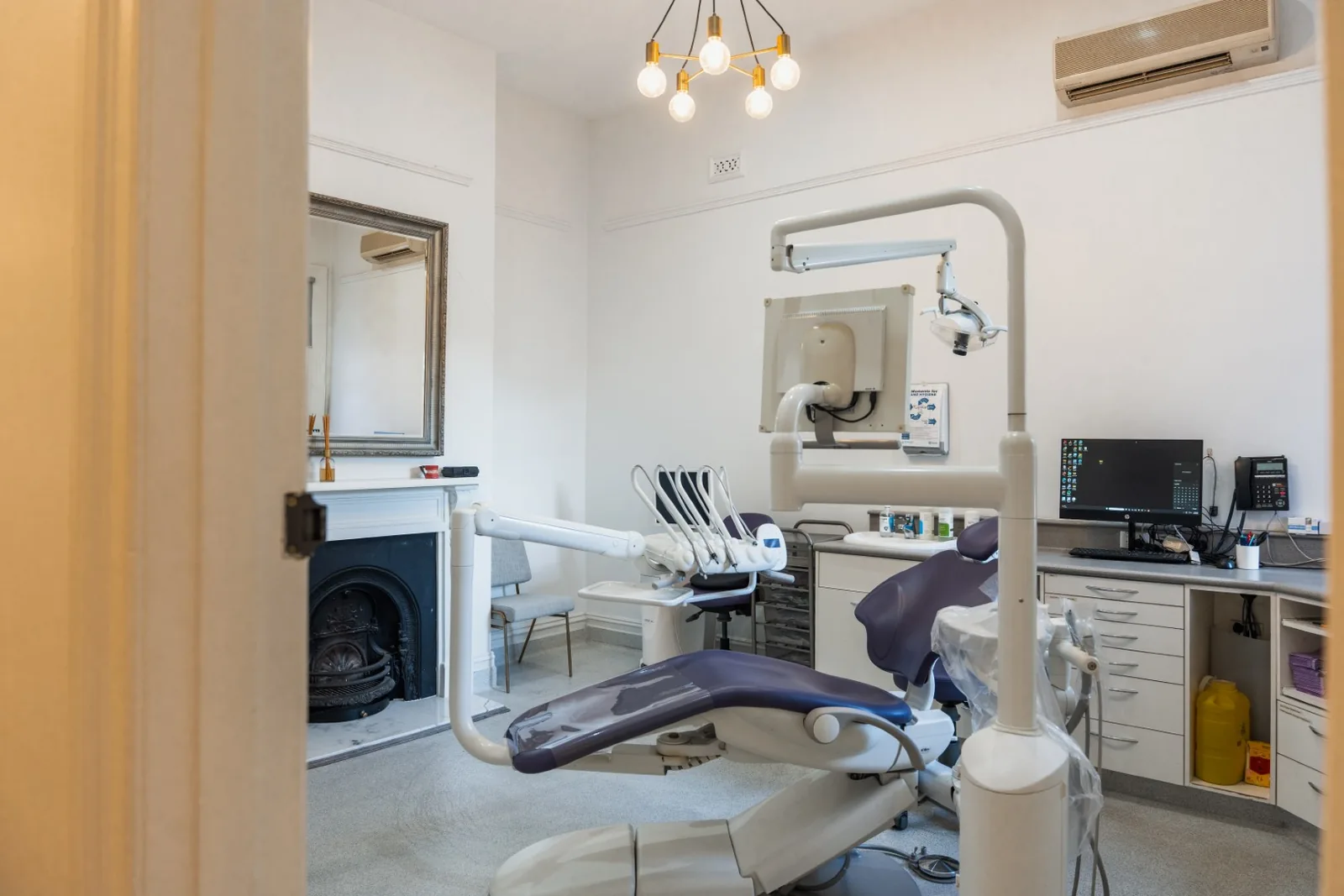Treatment room at TMJ Therapy Centre with heritage fireplace and dental chair
